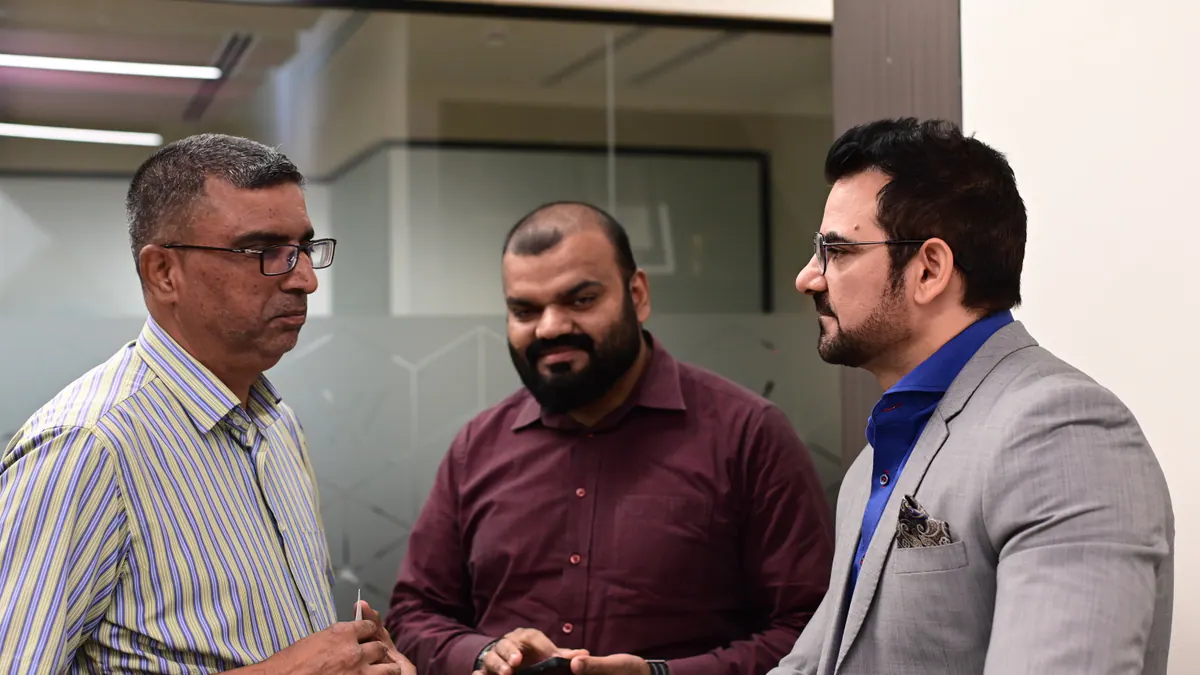 Three business leaders in a focused conversation at a Global Syndicate gathering